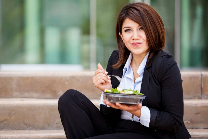 business woman eating a healthy salad and relaxing outdoors